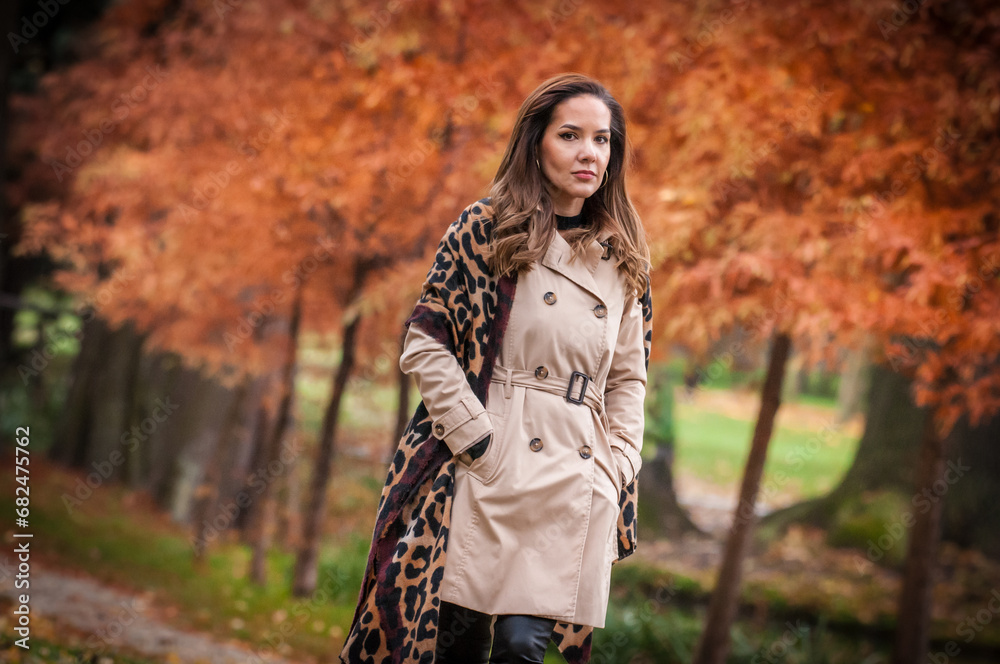 young girl in coat in forest. Fashion woman in coat in park. Slim young fashion model wearing white coat outdoor. Beautiful woman in leopard coat in the autumn park