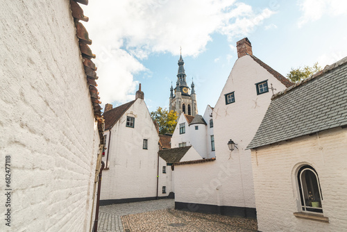 Historic centre of Begijnhof in Kortrijk with the Belfry of Courtrai in the background. A collection of individual and/or communal houses, houses and monasteries of the Beguins