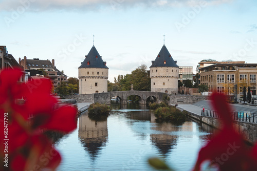 Kortrijk town centre with two historic towers on the riverside. Flowers, river and historic buildings. Belgian city in the south of the country