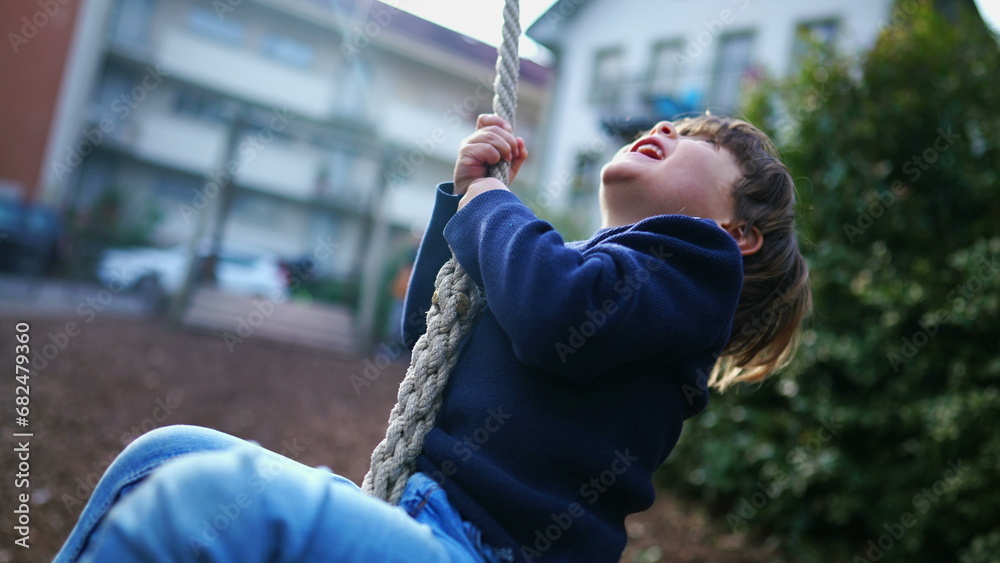 Obraz premium Child Holding Tight and Sliding to End of Wire Rope at Public Park, Young Boy Having Fun in Nostalgic Childhood Moment, Close-Up Slide on Park Wire