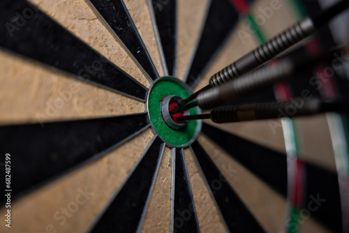 Dart in bulls eye of dartboard with shallow depth of field concept for hitting target.