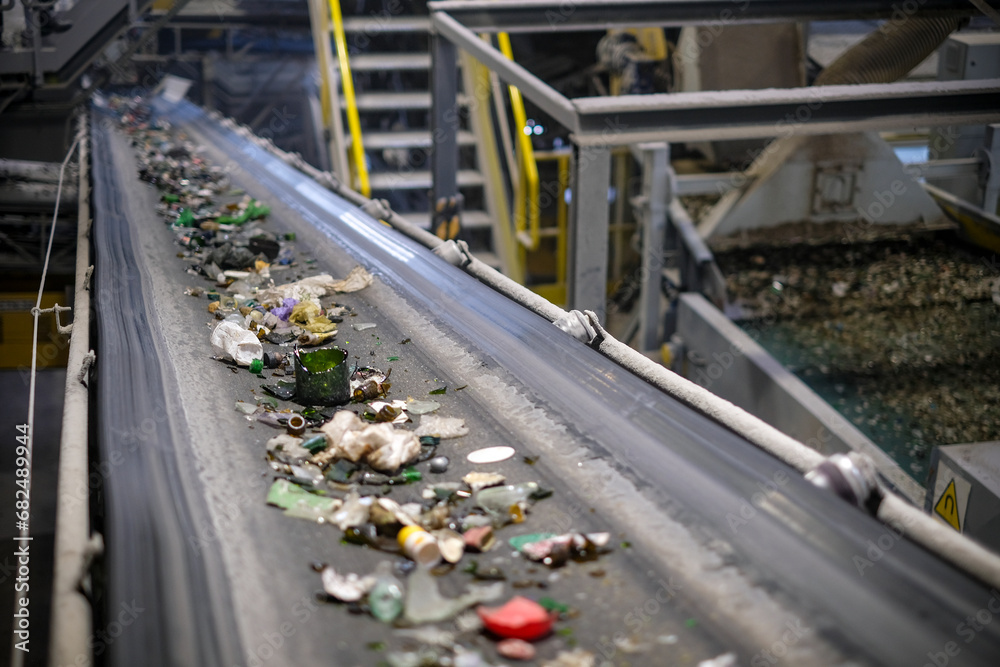 a belt transports glass material to be crushed for subsequent recycling