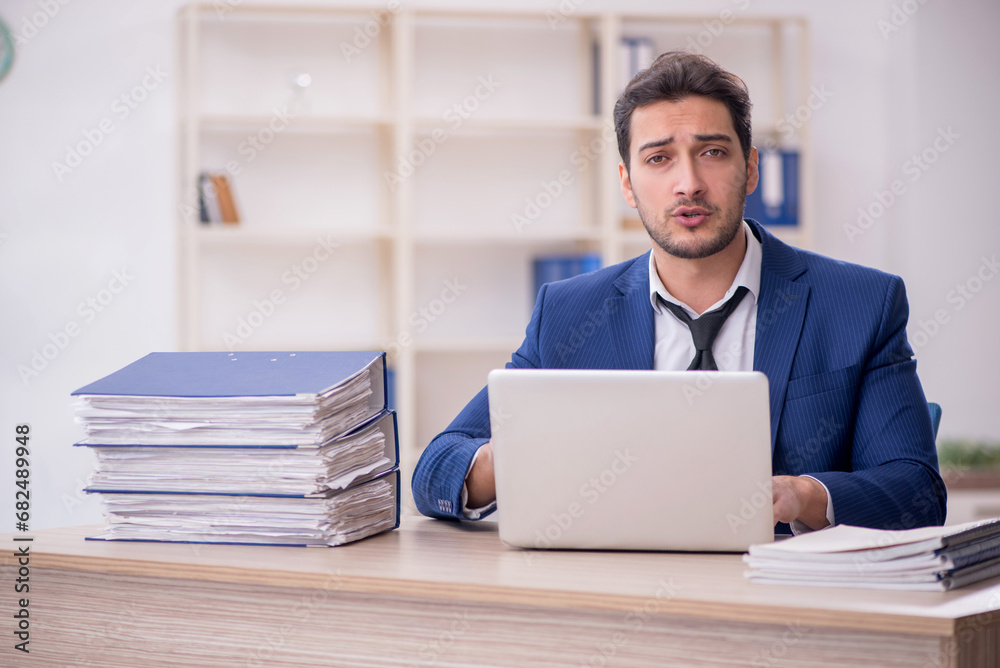 Young male employee and too much work in the office Young male employee and too much work in the office