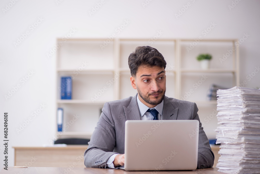Young male employee and too much work in the office Young male employee and too much work in the office