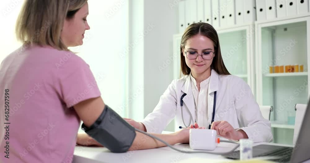 Doctor nurse student using a tonometer checks patient blood pressure in medical clinic. Hypertension during pregnancy causes and symptoms Doctor nurse student using a tonometer checks patient blood pressure in medical clinic. Hypertension during pregnancy causes and symptoms