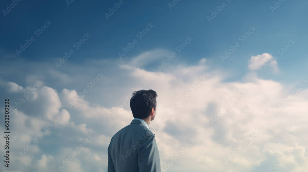 Back view of young businessman looking away against blue sky with white clouds Back view of young businessman looking away against blue sky with white clouds