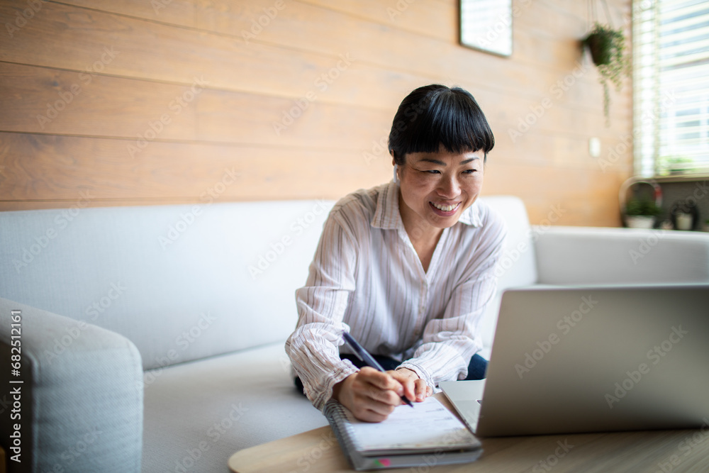 Focused Asian Woman Working on Laptop in Modern Home Interior Focused Asian Woman Working on Laptop in Modern Home Interior