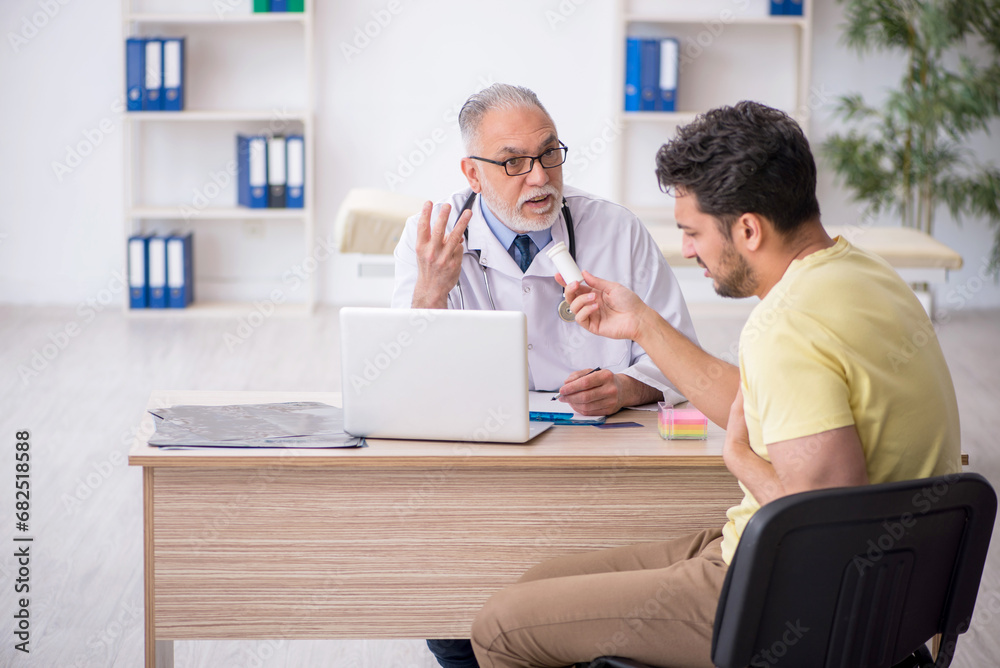 Obraz premium Young male patient visiting old male doctor