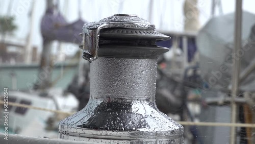Drops of autumn rain break on the winch of a sailing yacht in the harbor. Slow motion.