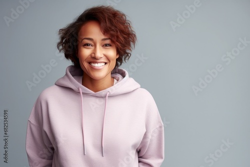 portrait of a african american mid age smiling woman in hoodie on grey background photo