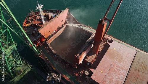 Aerial view of big cargo ship bulk carrier is loaded with grain of wheat in port at sunset photo