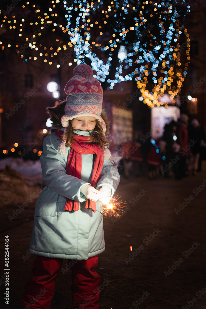 a little girl is enjoying a burning bengal wildebeest on the background of Christmas lights.