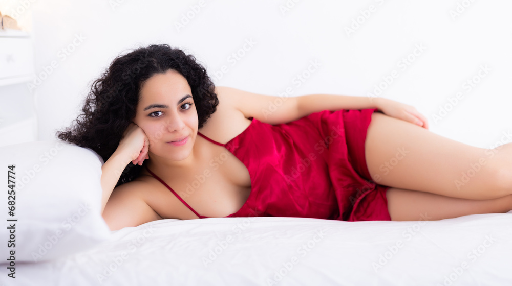 Naklejka premium Portrait of sexy brunette woman in red lingerie enjoying lying in bed