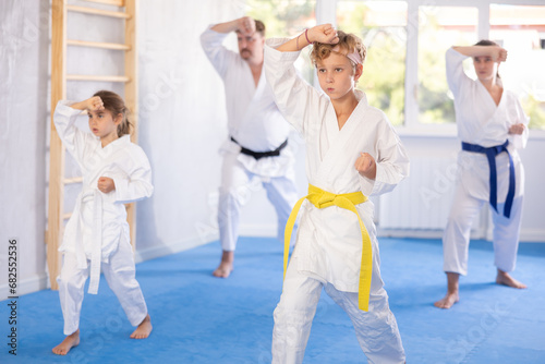 Parents with children athletes starting position and studying repeating sequence of punches and painful techniques in karate kata technique. Oriental martial arts, training and obtaining black belt