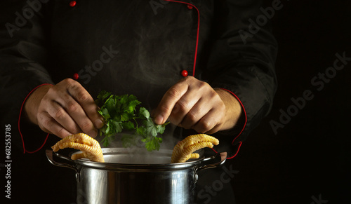 Vászonkép The cook adds fresh parsley to a pot of boiling chicken legs