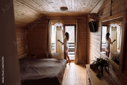 morning of the bride in the hotel room. The bride is preparing for the wedding ceremony. The girl puts on a dress.