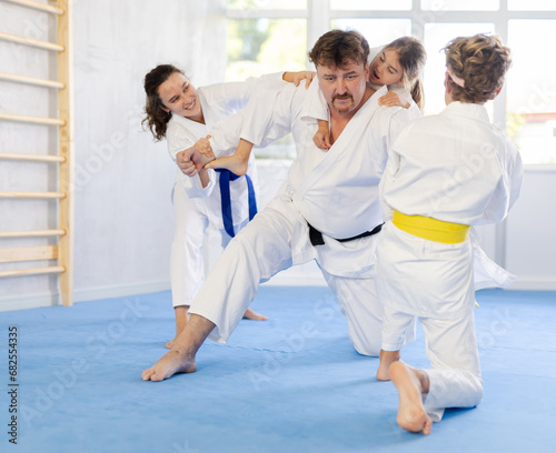 During martial arts training, father of family repels attack of whole family. Parents and children have fun in gym after workout