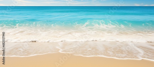On a beautiful beach in the midst of summer, an abstract texture of water gently caresses the soft sand, as travelers revel in the concept of tranquility and relaxation, indulging in a refreshing hand