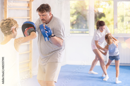 Father and son wearing boxing gloves practice boxing technique in gym