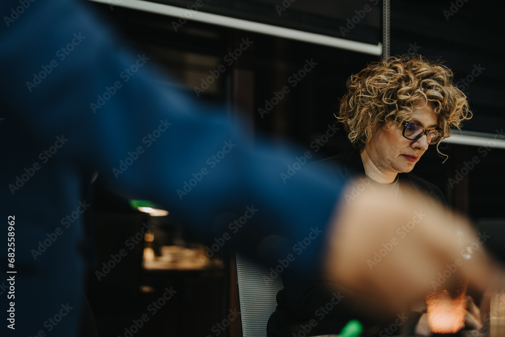 Diverse business team collaborating on projects and analyzing reports for financial growth in a creative office. Working late night and meeting deadlines with determination.