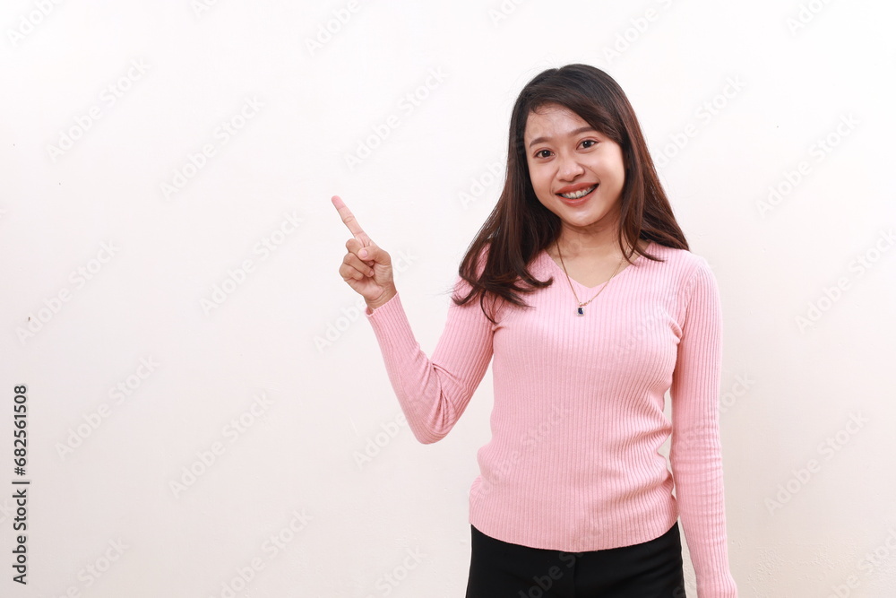 Happy smiling young asian girl standing while pointing sideways. Advertisement and promotional concept. Isolated on white background Happy smiling young asian girl standing while pointing sideways. Advertisement and promotional concept. Isolated on white background