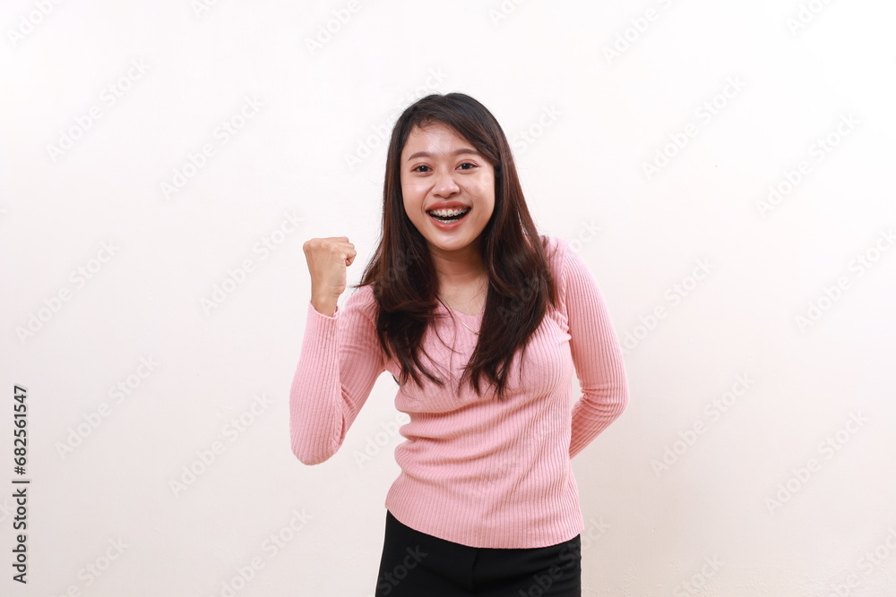 Joyful excited young asian girl celebrating victory with fist hands. Isolated on white