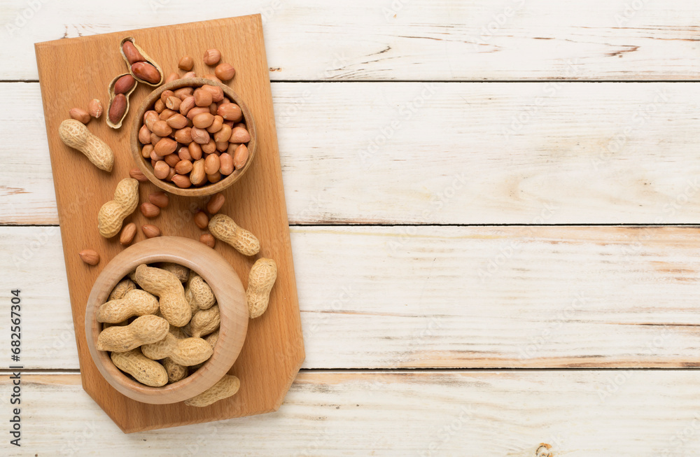 Peeled and unpeeled peanuts on wooden background, top view Peeled and unpeeled peanuts on wooden background, top view