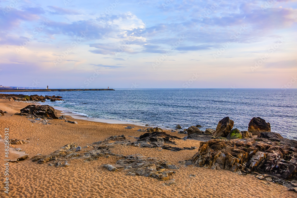 Landscape of the picturesque sandy coast of the Atlantic Ocean with large brown stones at sunset. Porto, Portugal. Landscape of the picturesque sandy coast of the Atlantic Ocean with large brown stones at sunset. Porto, Portugal.