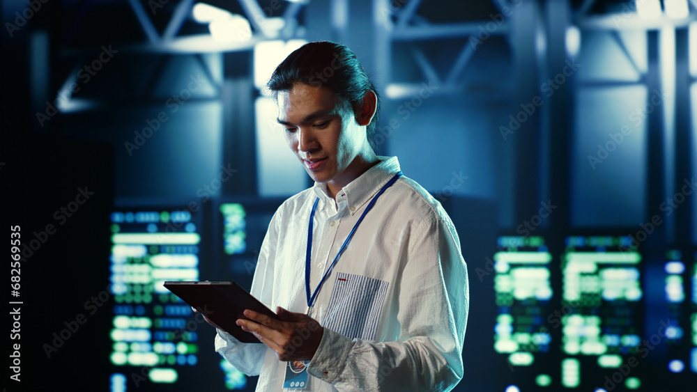Fototapeta premium Proactive employee walking through data center electronics providing processing resources for different workloads. Organized engineer evaluating server rigs tasked with solving complex operations