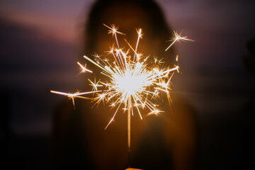 woman holding sparkles celebrating on tropical beach