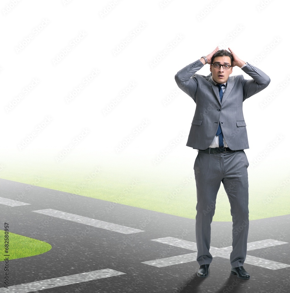 Young businessman at crossroads in uncertainty concept Young businessman at crossroads in uncertainty concept