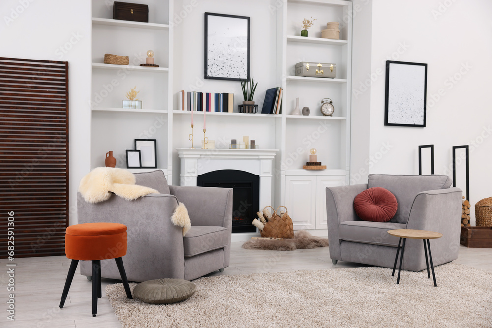 Comfortable armchairs, fireplace and shelves in living room. Interior design Comfortable armchairs, fireplace and shelves in living room. Interior design