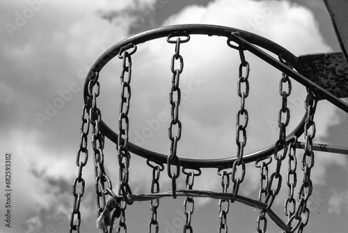 In a big city, between multi-story buildings, boys made a net for a basketball ring out of chain. © SERHII