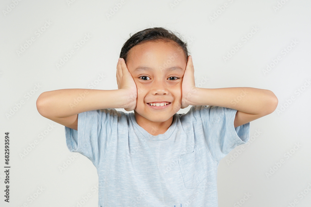 boy, holding head with both hands, not wanting to hear, while smiling isolated over white background boy, holding head with both hands, not wanting to hear, while smiling isolated over white background
