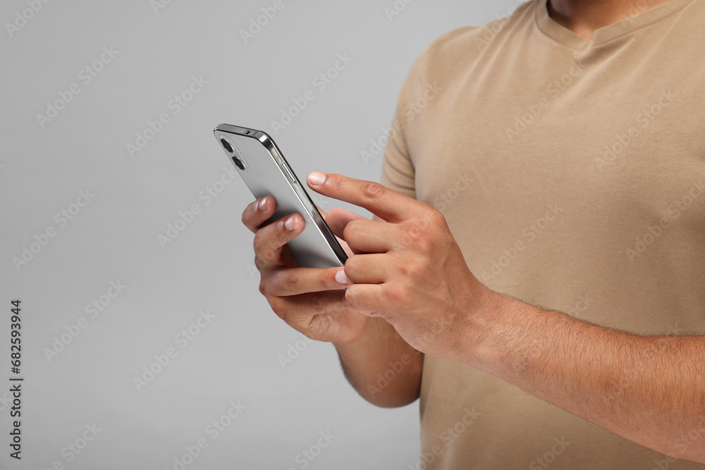 Man sending message via smartphone on grey background, closeup. Space for text Man sending message via smartphone on grey background, closeup. Space for text