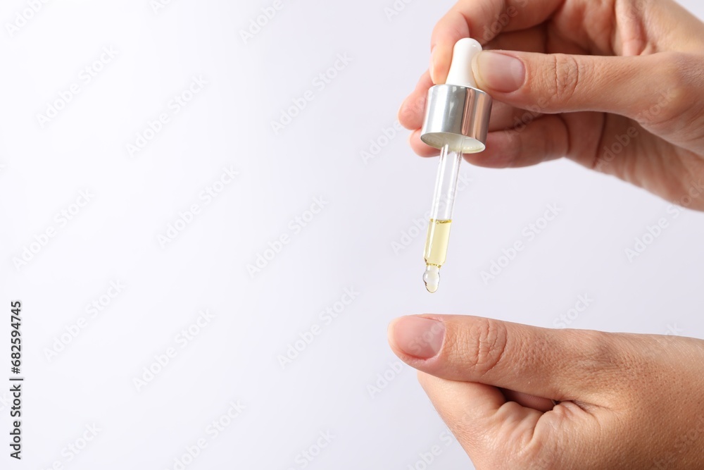 Woman applying cosmetic serum onto her finger on white background, closeup. Space for text Woman applying cosmetic serum onto her finger on white background, closeup. Space for text