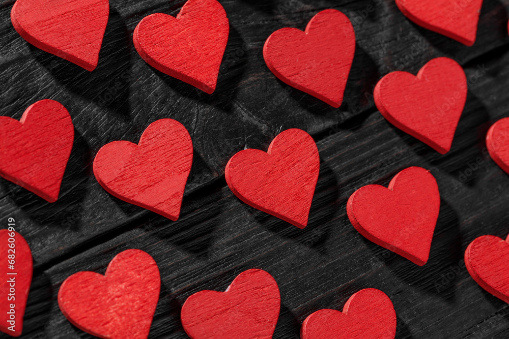 Fototapeta premium Red wooden hearts on black wooden background