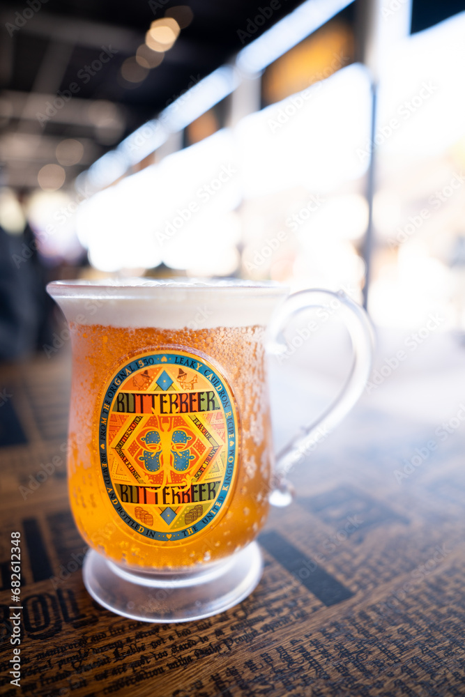 Fototapeta premium JAPAN - NOV 13, 2023: Delicious BUTTERBEER craft drink alcohol free with honey bee vintage label on a glass in Warner Bros. Studio Tour Tokyo, The Making of Harry Potter