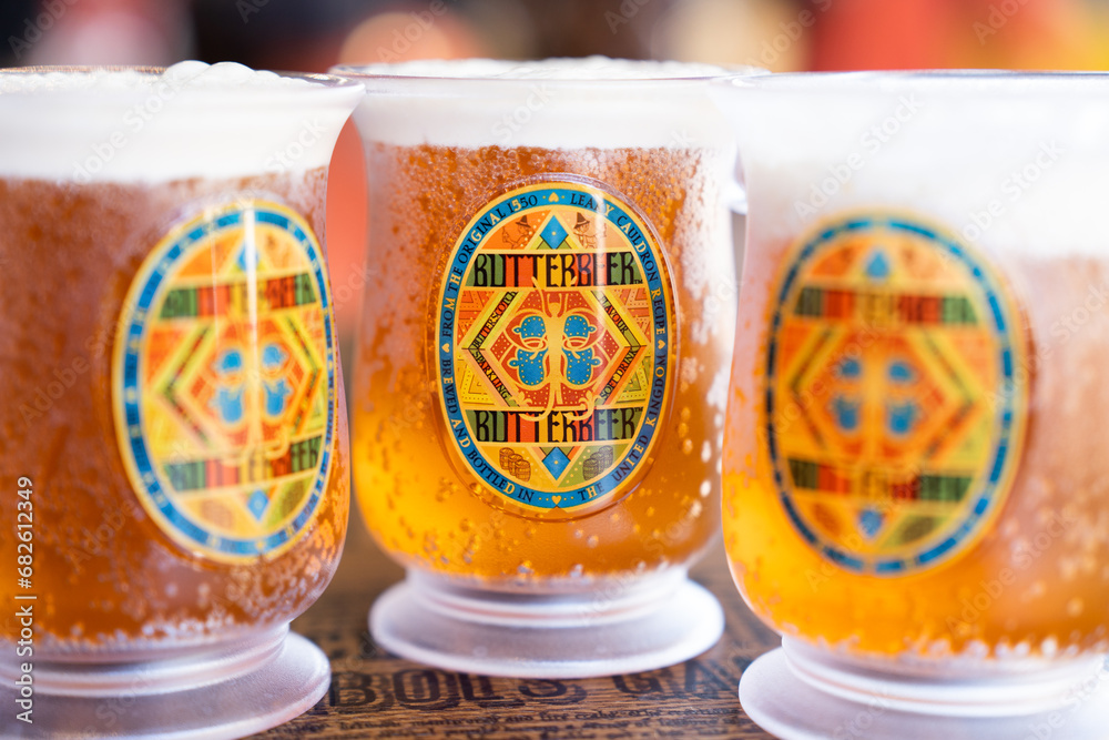 Fototapeta premium JAPAN - NOV 13, 2023: Three glass of BUTTERBEER alcohol free cold drink with white foam and close up honey bee logo on label in Warner Bros. Studio Tour Tokyo, The Making of Harry Potter