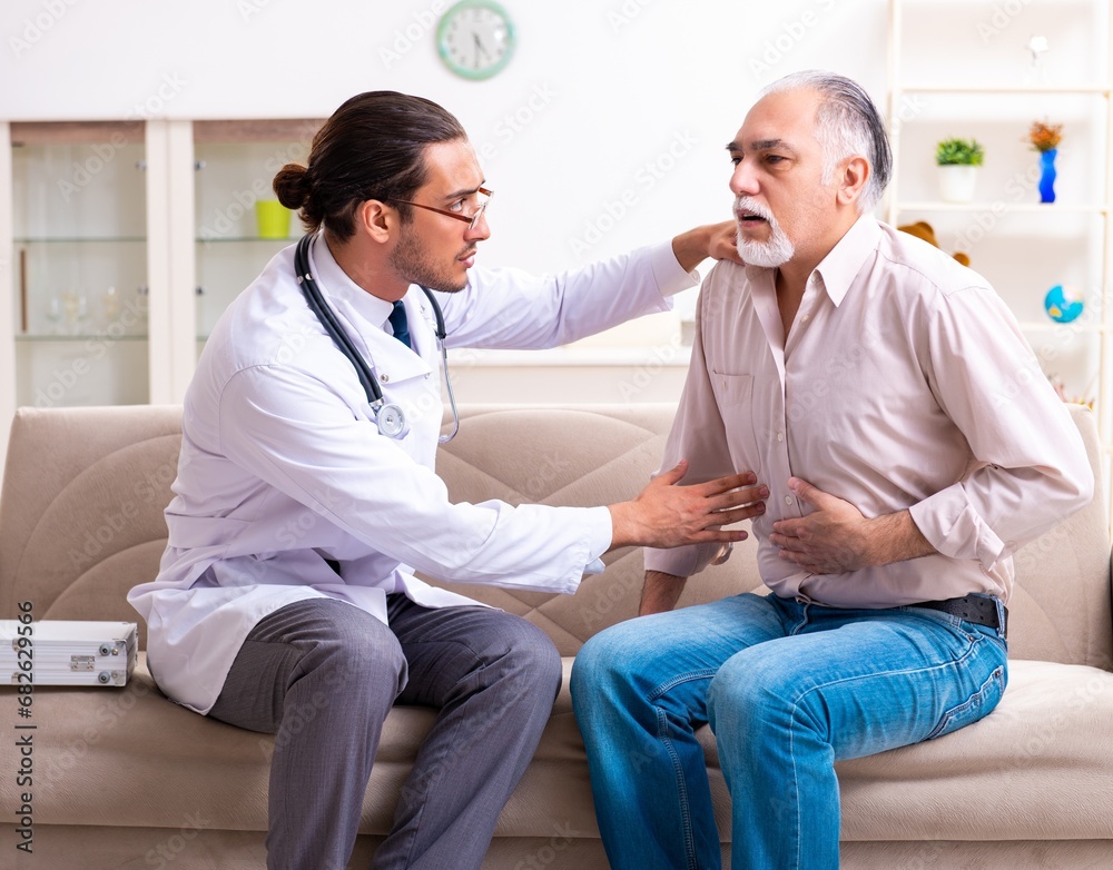 Fototapeta premium Young male doctor visiting old patient at home