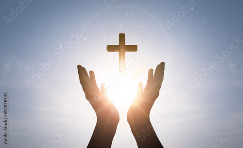 Brightly shining sunlight and Silhouette of cross in human hand