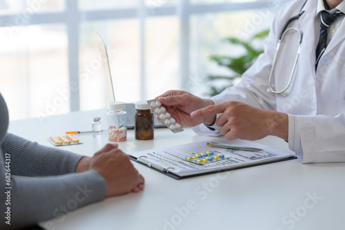 Doctor, pharmacist pointing at pill bottle, giving advice, recommending how to take medicine to female patient, explaining prescription to business woman Medical and health care system. photo