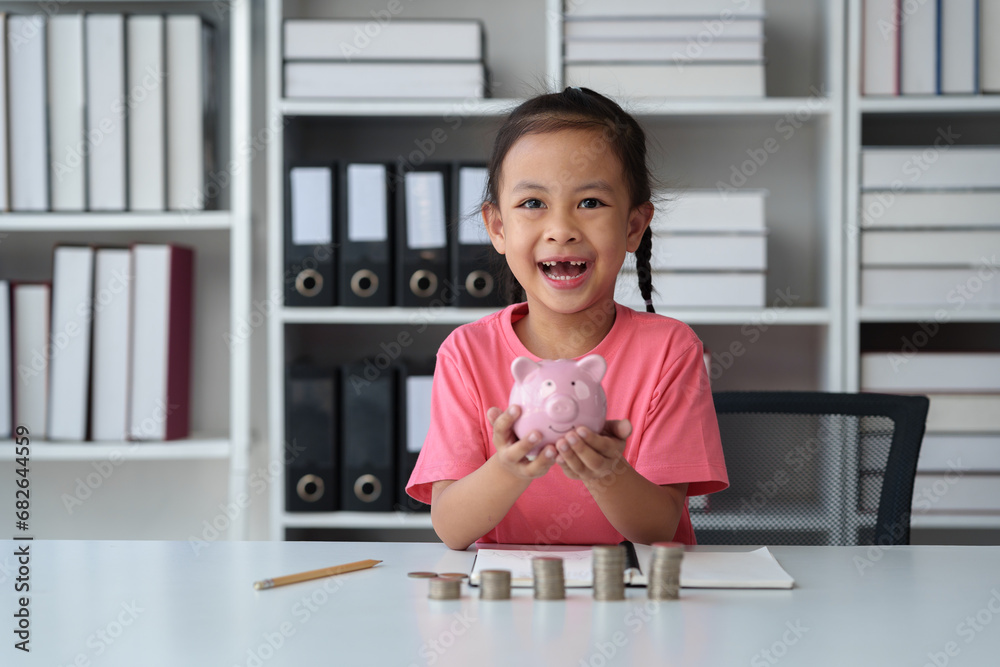 Cute little Asian girl playing with coins, making money in piles, putting money in a piggy bank. Count your saved coins and learn about frugality. Educational planning, management, future concepts. Cute little Asian girl playing with coins, making money in piles, putting money in a piggy bank. Count your saved coins and learn about frugality. Educational planning, management, future concepts.