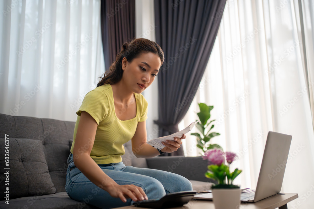 Woman using calculator to check total sum of household bills Woman using calculator to check total sum of household bills
