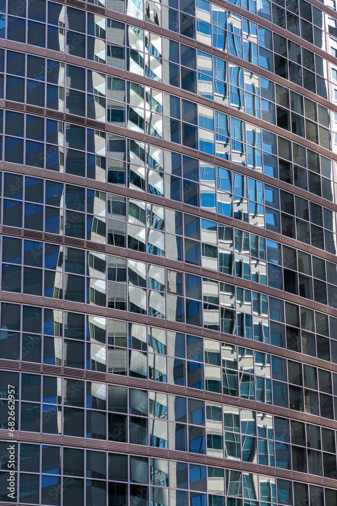 ガラス張りの高層オフィスビルに反射する高層ビル群