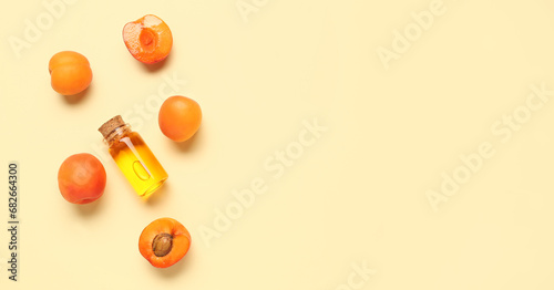 Bottle of essential oil and ripe apricots on beige background with space for text