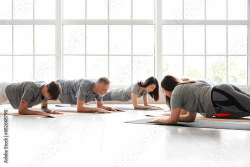 Group of sporty people doing plank in gym photo