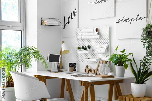 Interior of light office with workplace, pegboard and houseplants © Pixel-Shot
