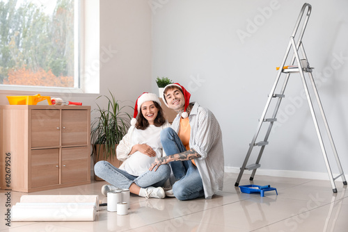 Young pregnant couple with Santa hats during repair in their new house