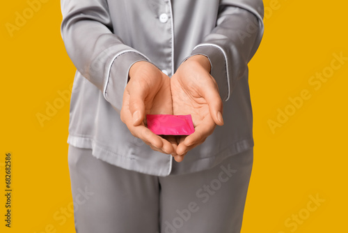 Beautiful young woman with condom on yellow background, closeup. Safe sex concept photo